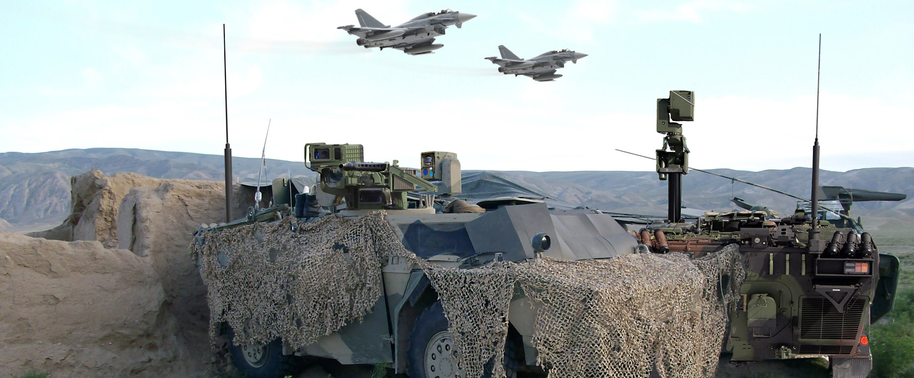 Two Eurofighter Typhoon aircraft flying over two camouflaged FENNEK reconnaissance vehicles