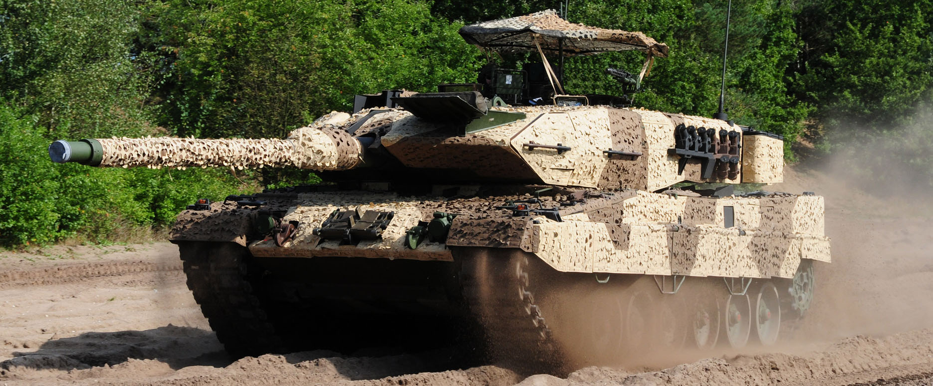 LEOPARD 2 Kampfpanzer fährt durch trockenen Boden aus Erde am Waldrand