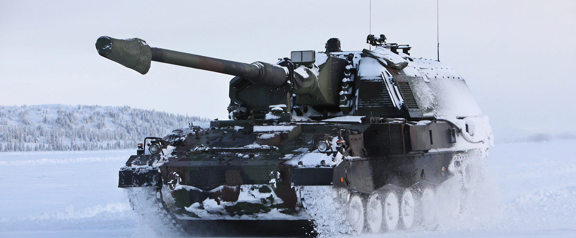 PzH2000 armoured howitzer driving into snowy landscape and kicking up snow