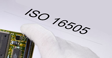 Auf einem Dokument steht ISO 16505 geschrieben, darüber ist der Ausschnitt einer Elektronikplatine zu sehen.