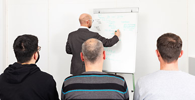 Instructor writing on flipchart with three people watching