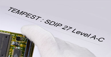 Auf einem Dokument steht TEMPEST: SDIP 27 Level A - C geschrieben, darüber ist der Ausschnitt einer Elektronikplatine zu sehen.