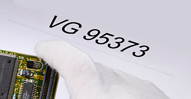 Auf einem Dokument steht VG 95373 geschrieben, darüber ist der Ausschnitt einer Elektronikplatine zu sehen.
