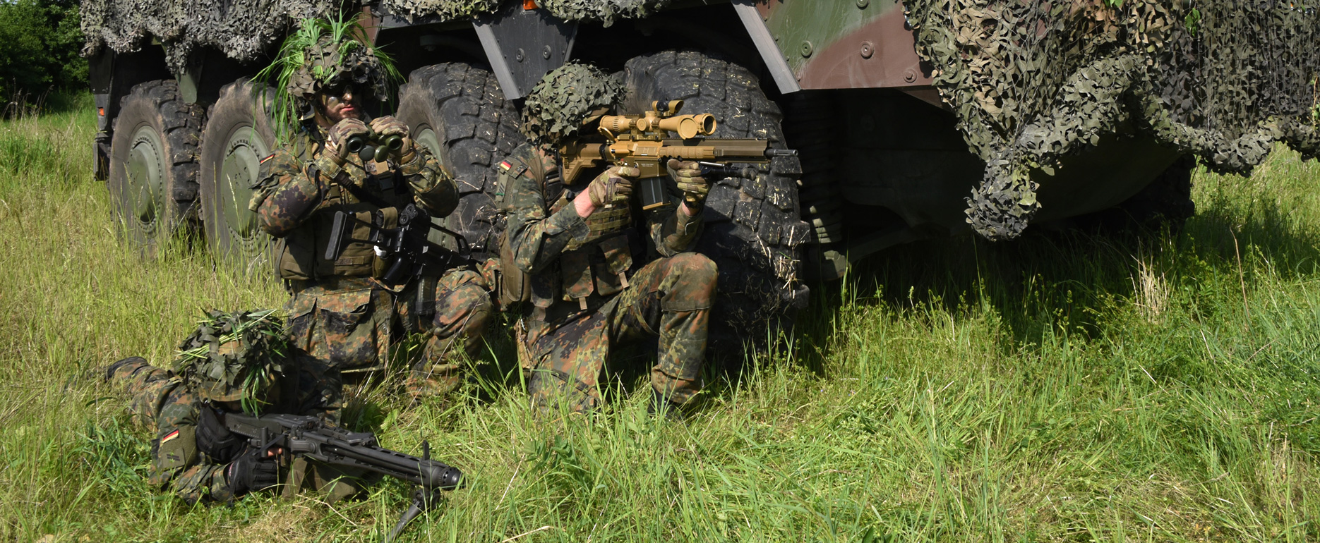 Soldiers take cover in front of a BOXER wheeled armoured vehicle